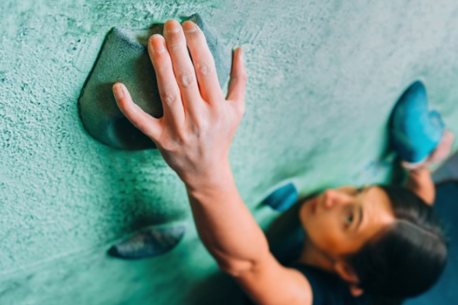 woman climbing up a climbing wall