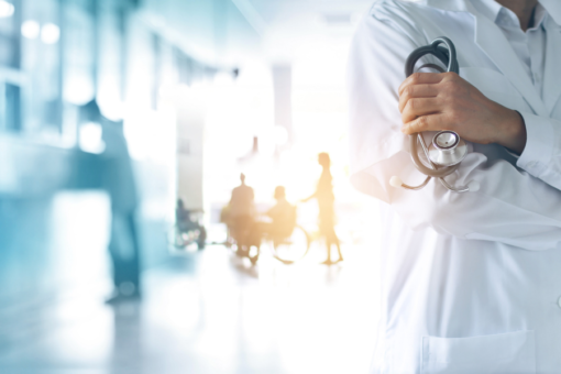 doctor holding a stethoscope and patients in background of hospital